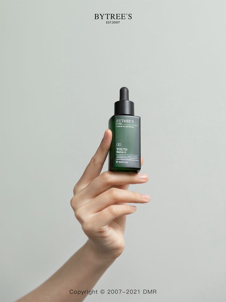 This May Contain: A Hand Holding Up A Bottle Of Green Toned Skin Care Product In Front Of Creative Design Generator Genflow テンプレートプレビュー